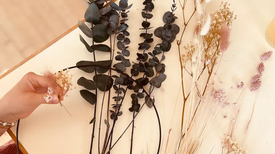 Hand arranging dried flowers on table.