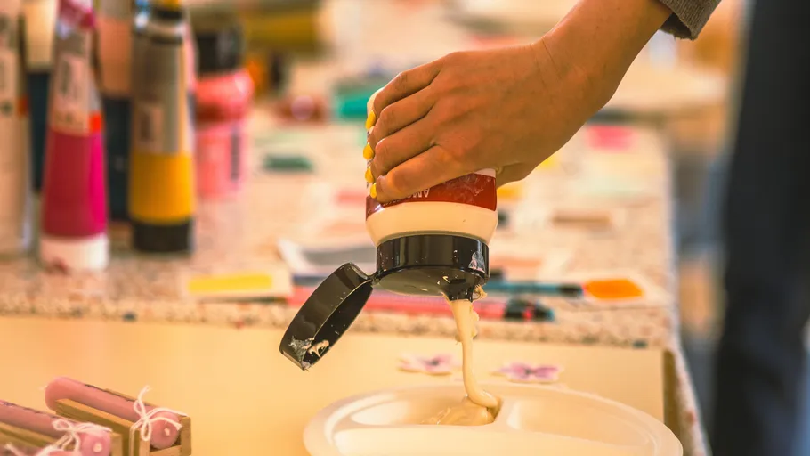 Hand pouring paint onto a plate in studio.