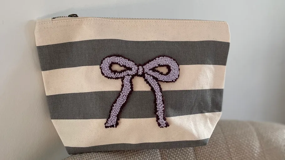 Striped pouch with a purple bow design.