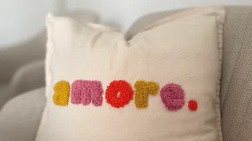 Kissen mit 'amore.'-Text auf Sofa.