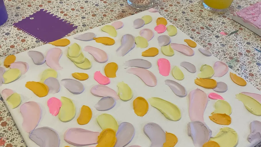 Canvas with colorful brush strokes on table.