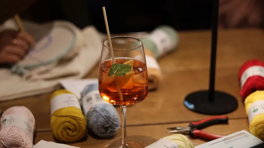 Cocktailglas auf Holztisch, Garn in der Nähe.