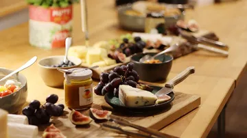 Käse, Obst und Marmelade auf Holztisch.