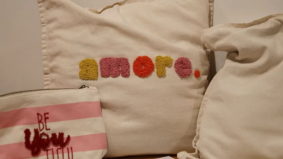 Cushions and pouch with embroidered text.