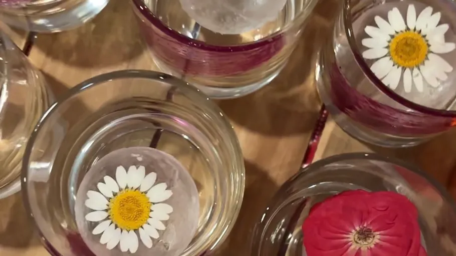 Gläser mit Eiskugeln und Blumen darin.