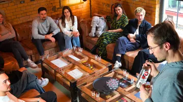 Gruppe sitzt um Tisch mit Getränken, drinnen.