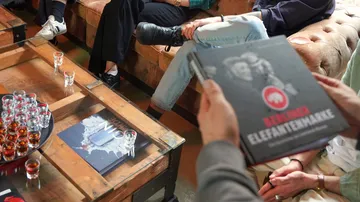 Books held, people seated, drinks on table.