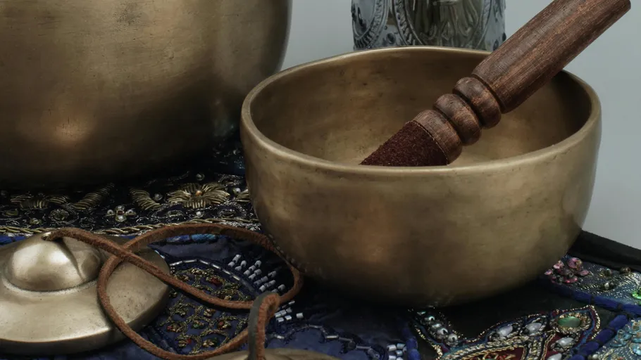 Klangschale und Schlegel auf besticktem Stoff.