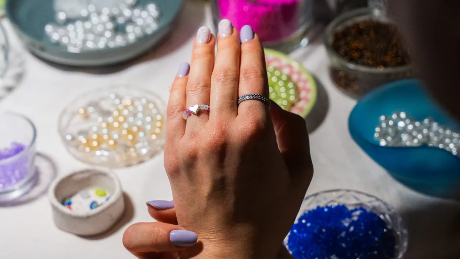 Hands modeling rings with beads nearby.