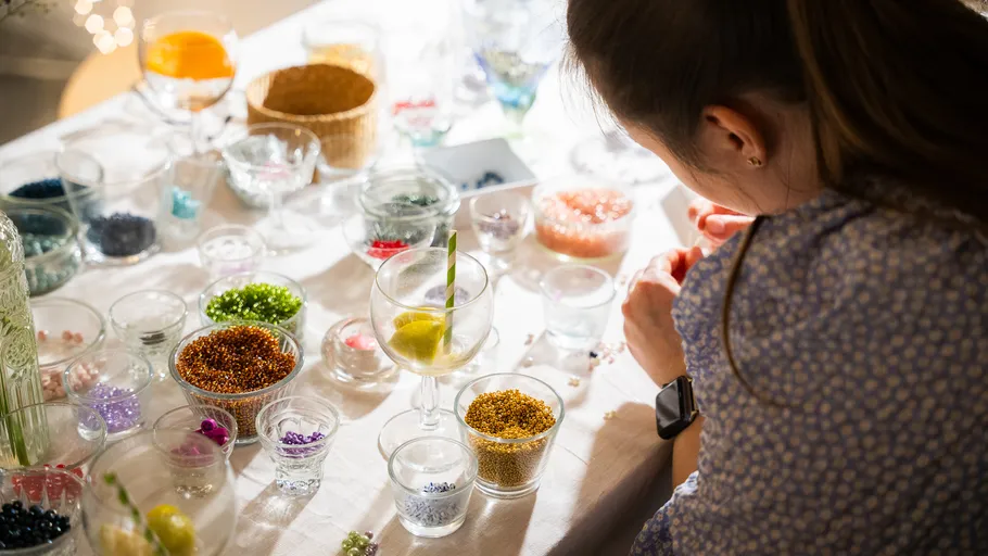 Woman crafting with colorful beads on table.