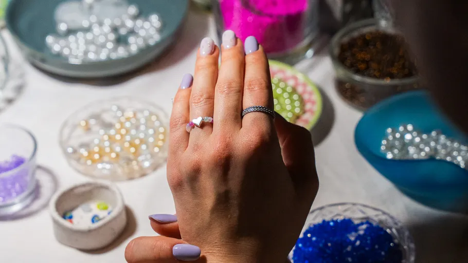 Hand with rings near colorful beads and bowls.