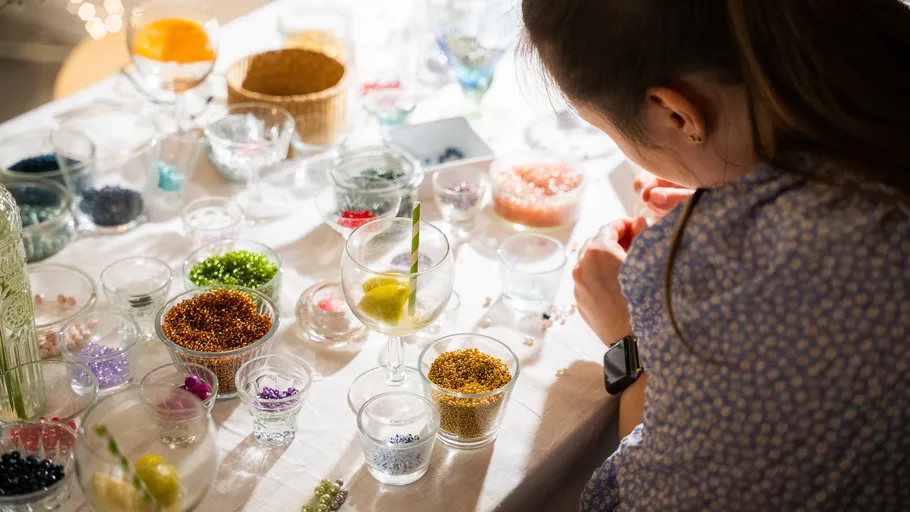 Woman crafting with beads on a table.