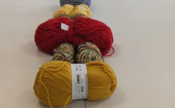 Balls of yarn lined up on table.