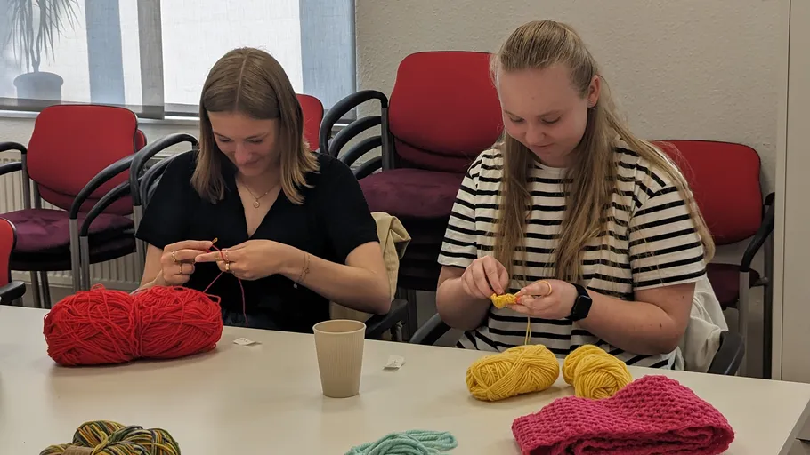 Zwei Frauen stricken in einem Besprechungsraum.