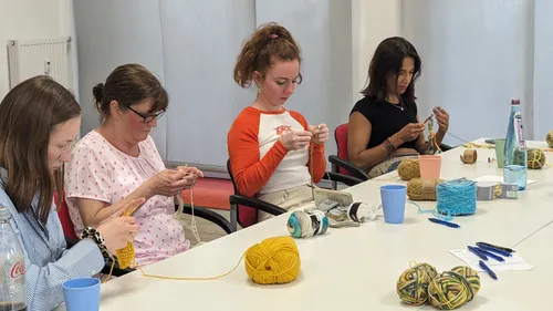 Fünf Frauen stricken an einem langen Tisch.