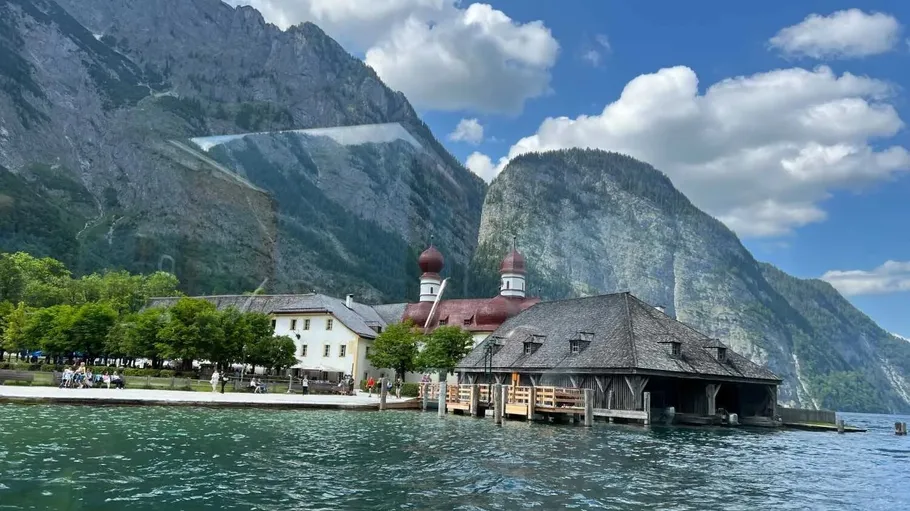 Kirche am See mit Bergen und Wolken.