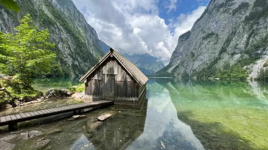 Wooden hut on lake between mountains.