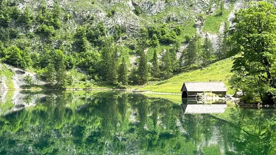 Bergsee mit Bootshaus und Spiegelungen.