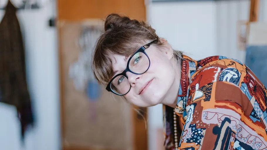 Person mit Brille lächelt drinnen.