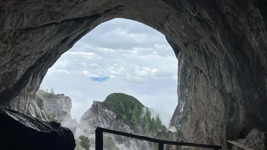 Cave entrance overlooking foggy mountain landscape.