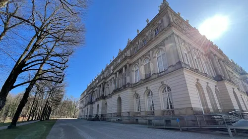 Historisches Schloss mit Bäumen an sonnigem Tag.