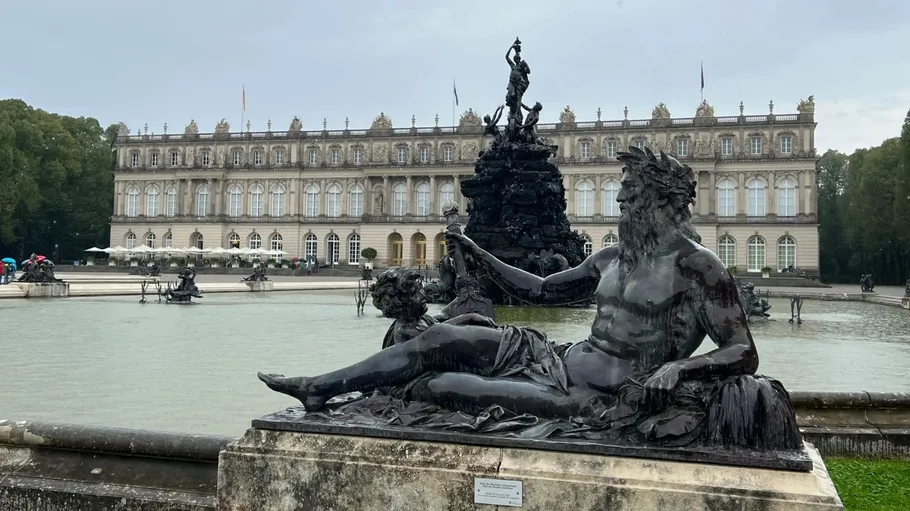 Statue by fountain in front of palace.