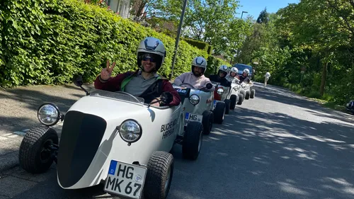 Personen fahren kleine Autos auf sonniger Straße.