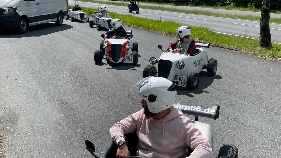 Menschen fahren kleine Autos auf einer Straße.