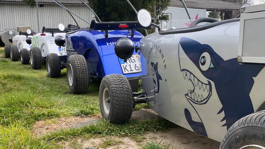 Mini cars in a row on grass.