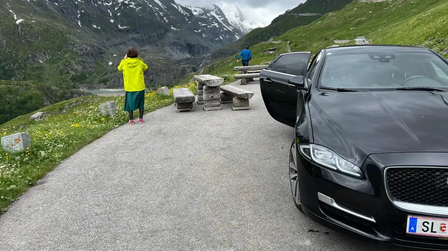 Car parked on mountain road, people sightseeing.