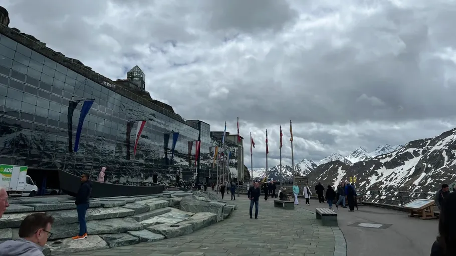 People walking by snowy mountains and flags.