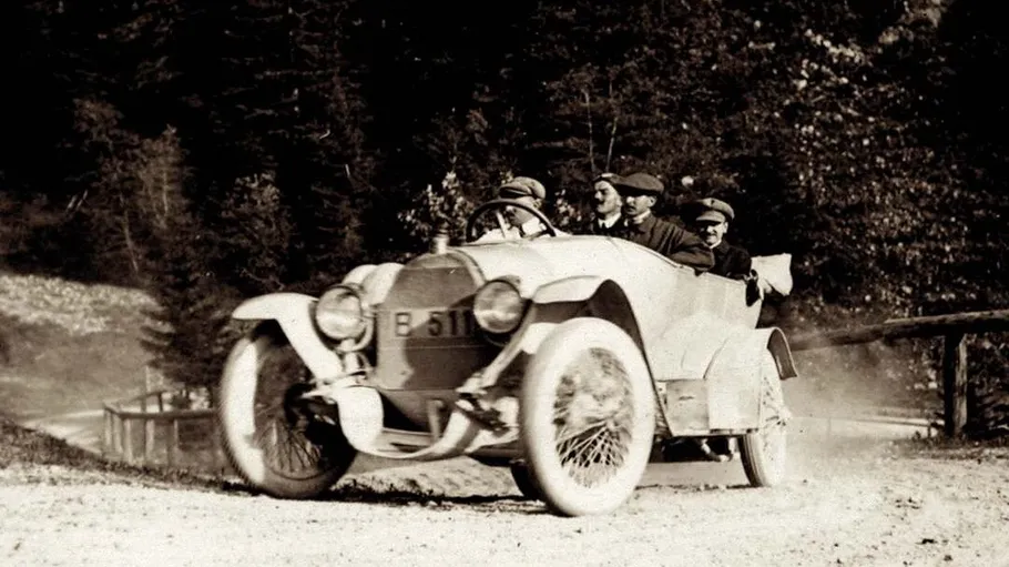 Vintage car driving on a dirt road.