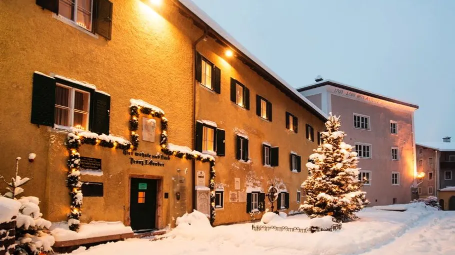 Schnee-bedecktes Gebäude mit Festbeleuchtung bei Dämmerung.