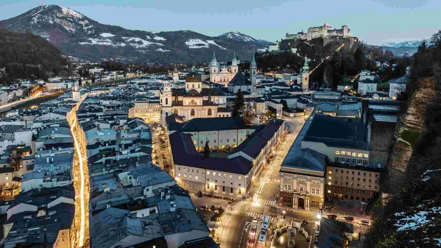 Stadtbild mit beleuchteten Straßen und Bergkulisse.