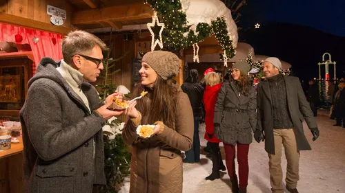 Paar isst auf einem festlichen Weihnachtsmarkt.