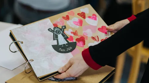 Person hält Album mit Herzen und Kritzelei.