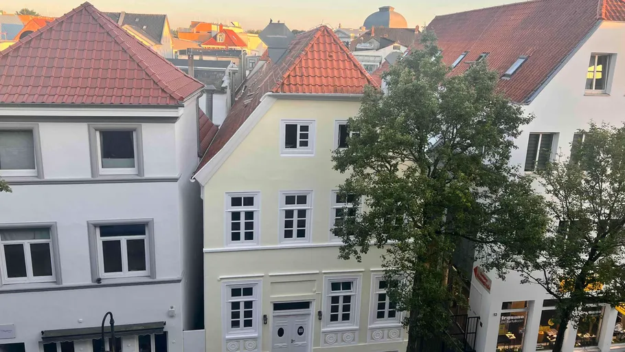 Three European houses with red roofs at sunset.