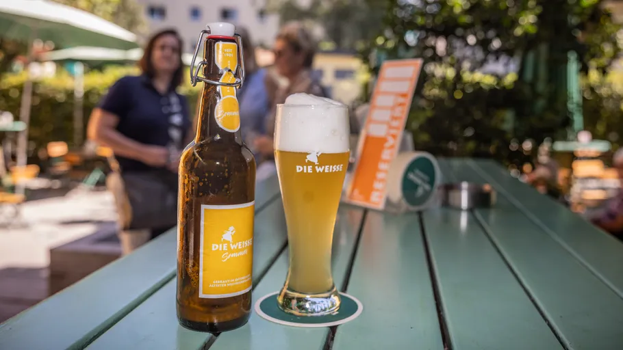 Bierflasche und Glas auf Außentisch.