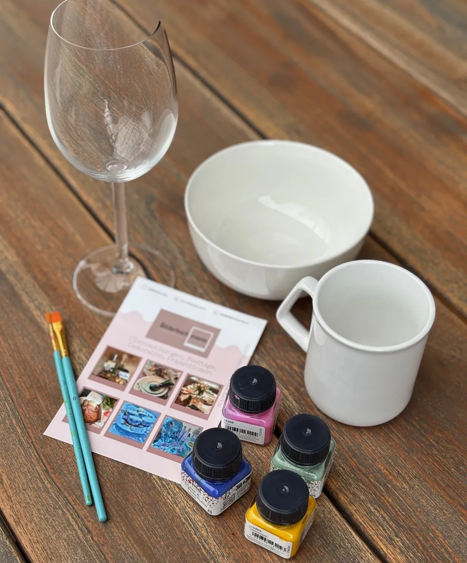 Art supplies and crockery on wooden table.