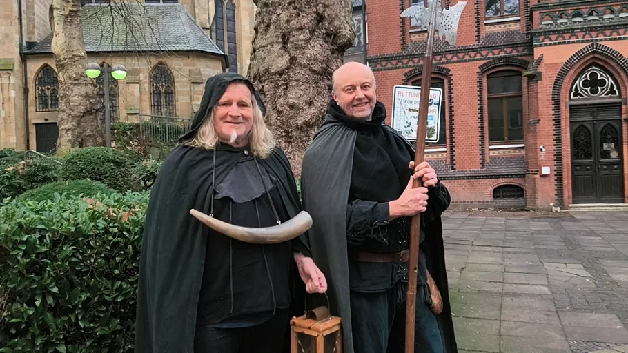 Two men in medieval costumes outside building.
