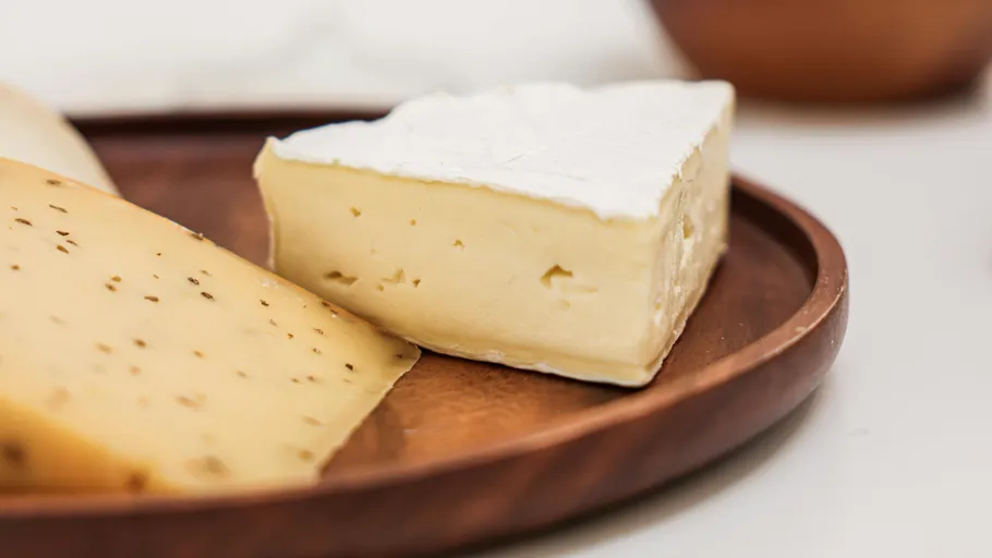 Cheese slices on a wooden plate.