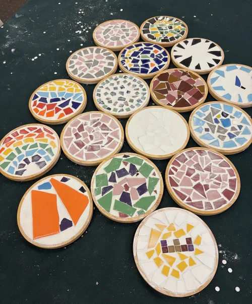 Colorful mosaic coasters on dark table.