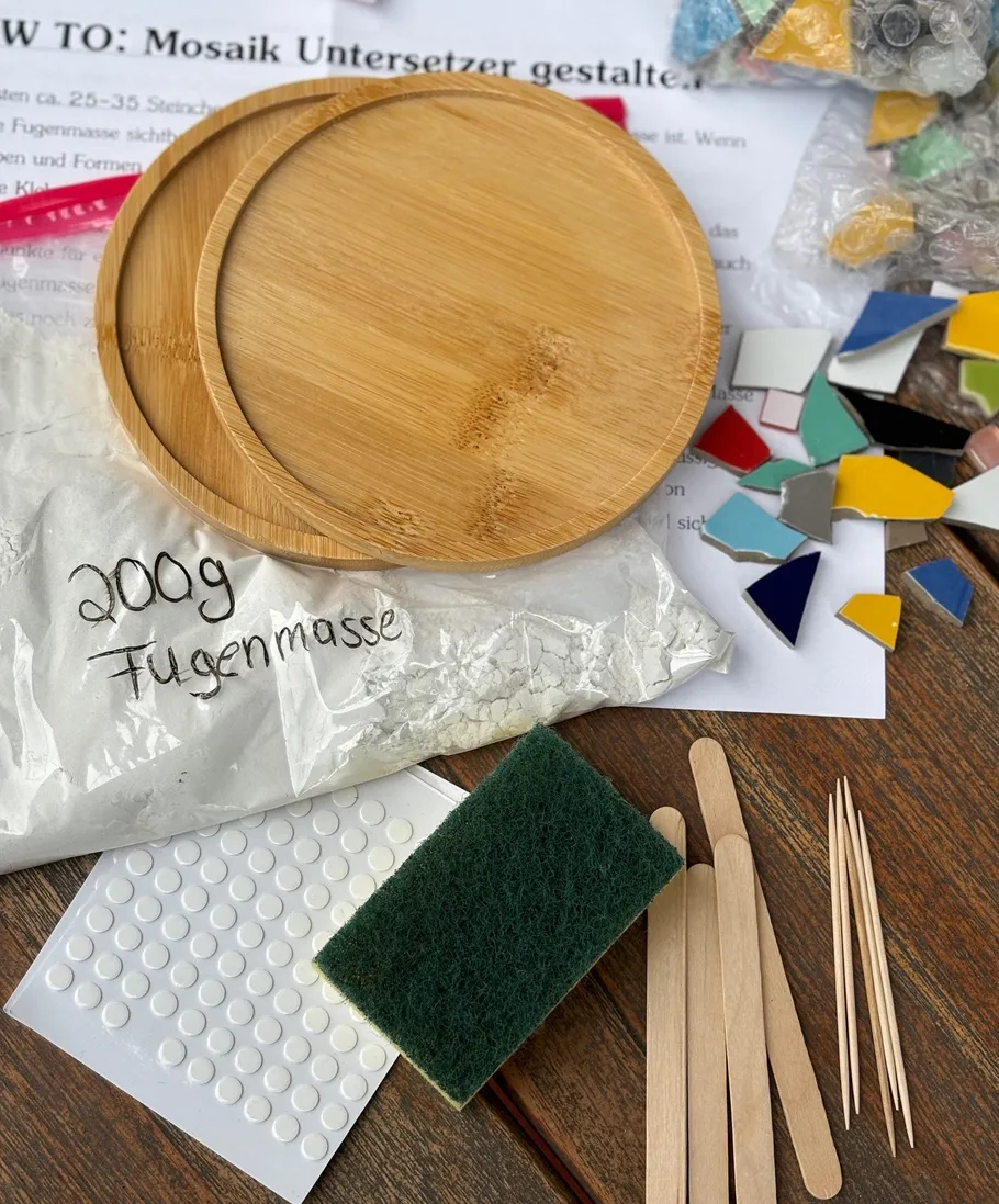 Mosaikset mit Fliesen und Werkzeugen auf Tisch.