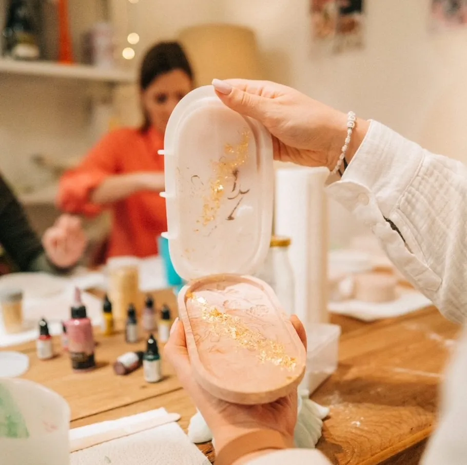Person holding mold with gold flakes, crafting workshop.