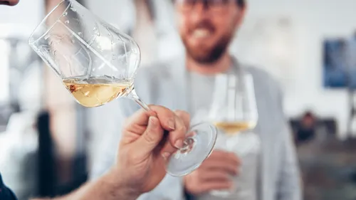 Person holding wine glass, smiling man blurred.