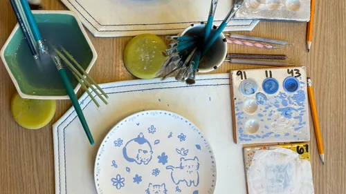 Painted plate with brushes and paints on table.