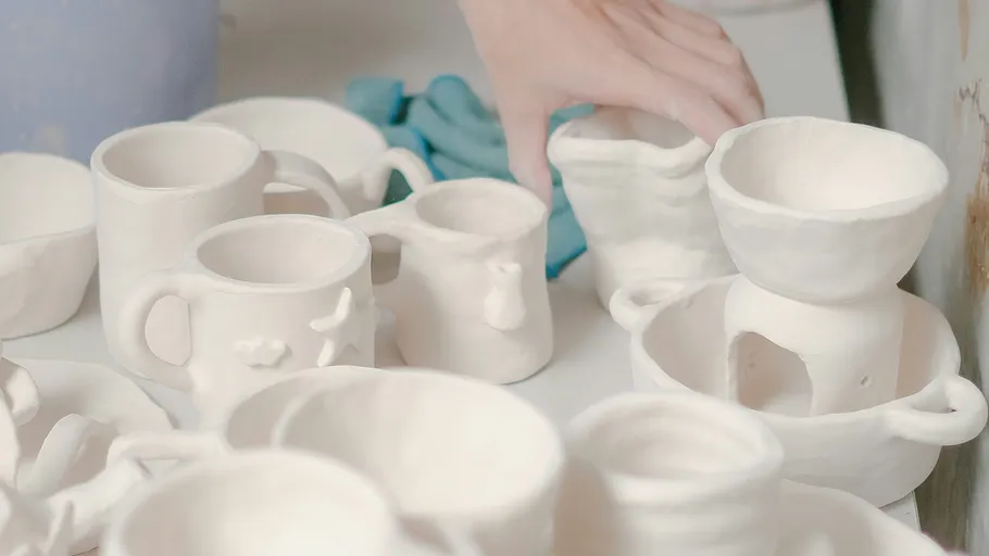 Hand arranging handmade pottery on a table.