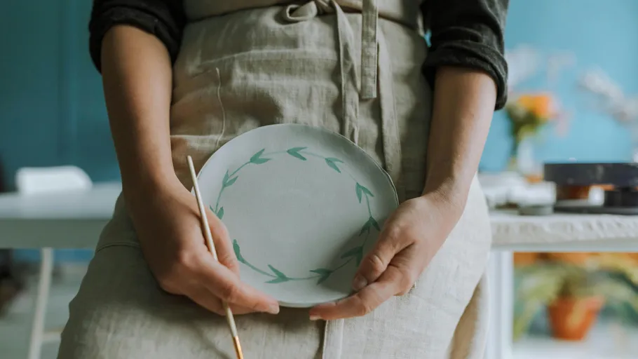 Person holding painted plate in studio.