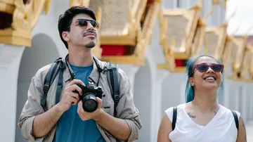 Two tourists admire temple architecture outdoors.