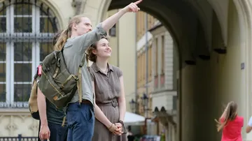 Two people in a city, one pointing upward.